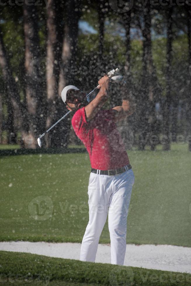 golfer hitting a sand bunker shot photo