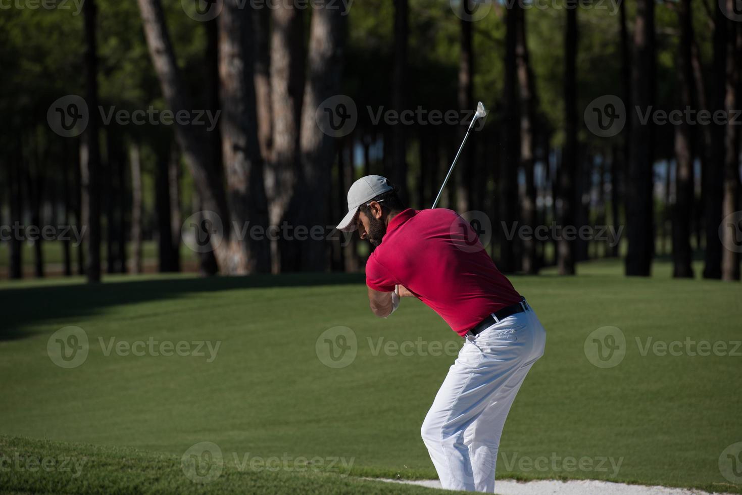 golfista golpeando un tiro de búnker de arena foto