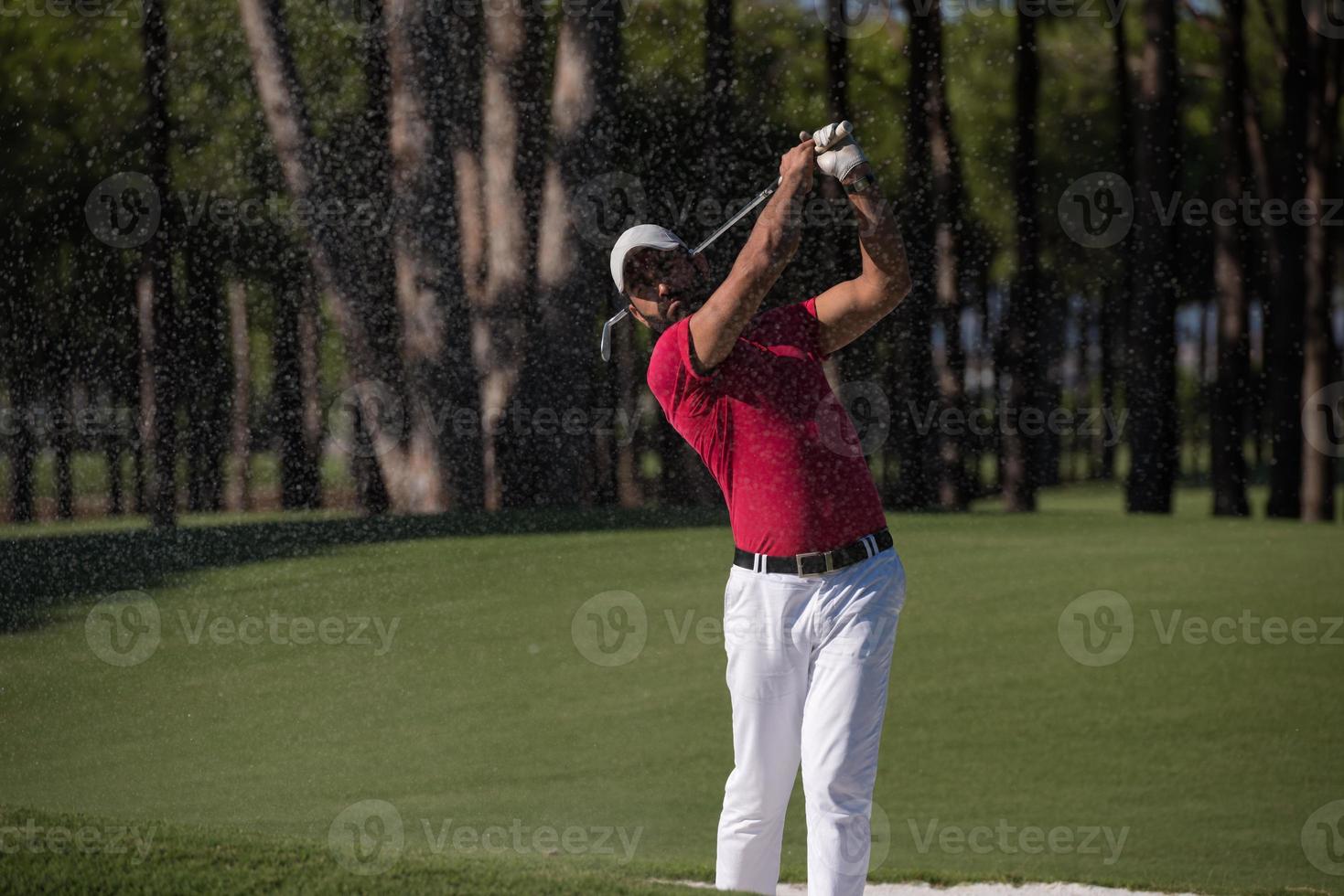 golfer hitting a sand bunker shot photo