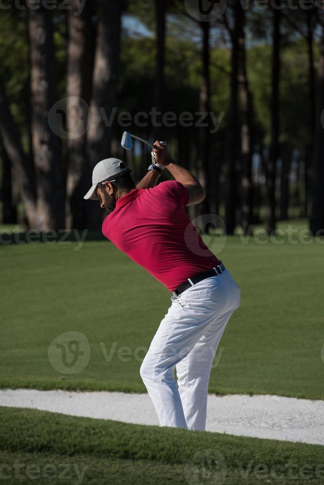 golfista golpeando un tiro de búnker de arena foto