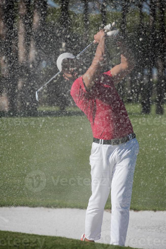 golfer hitting a sand bunker shot photo