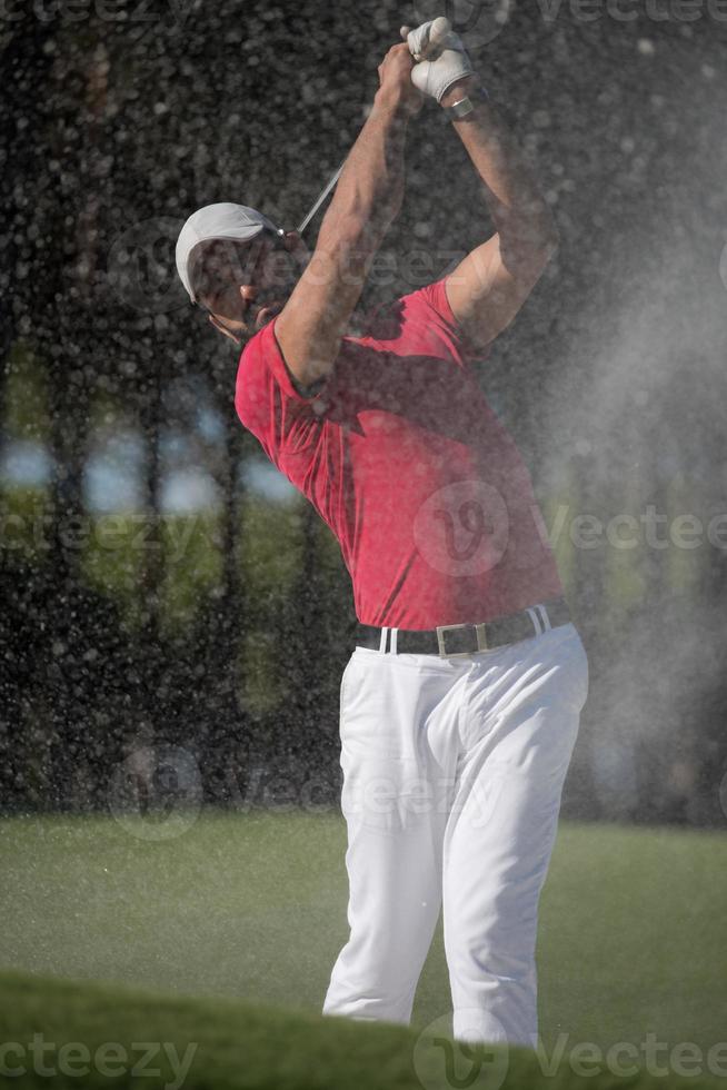 golfer hitting a sand bunker shot photo