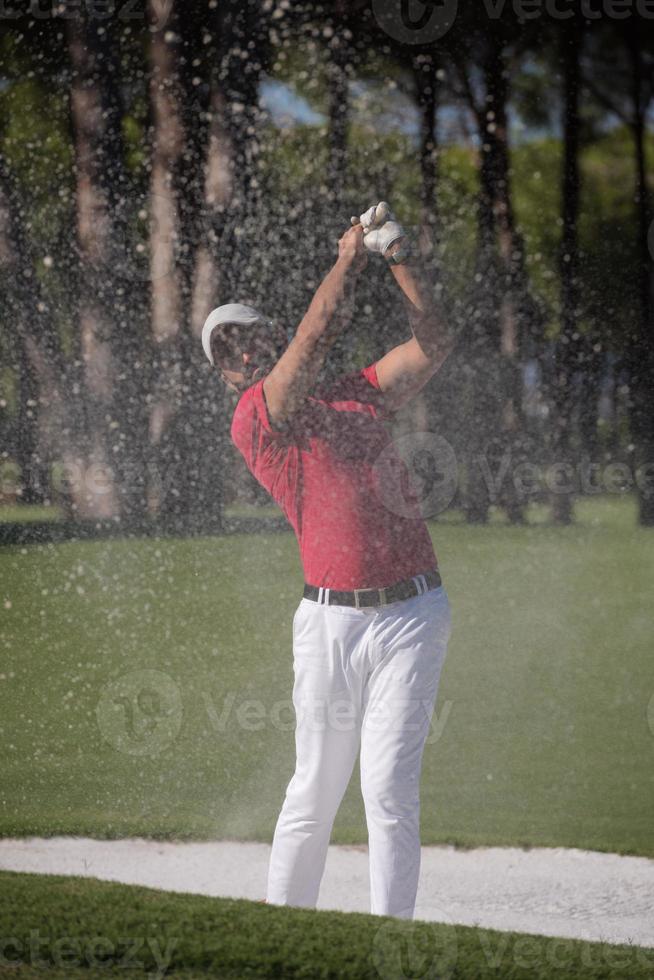 golfer hitting a sand bunker shot photo