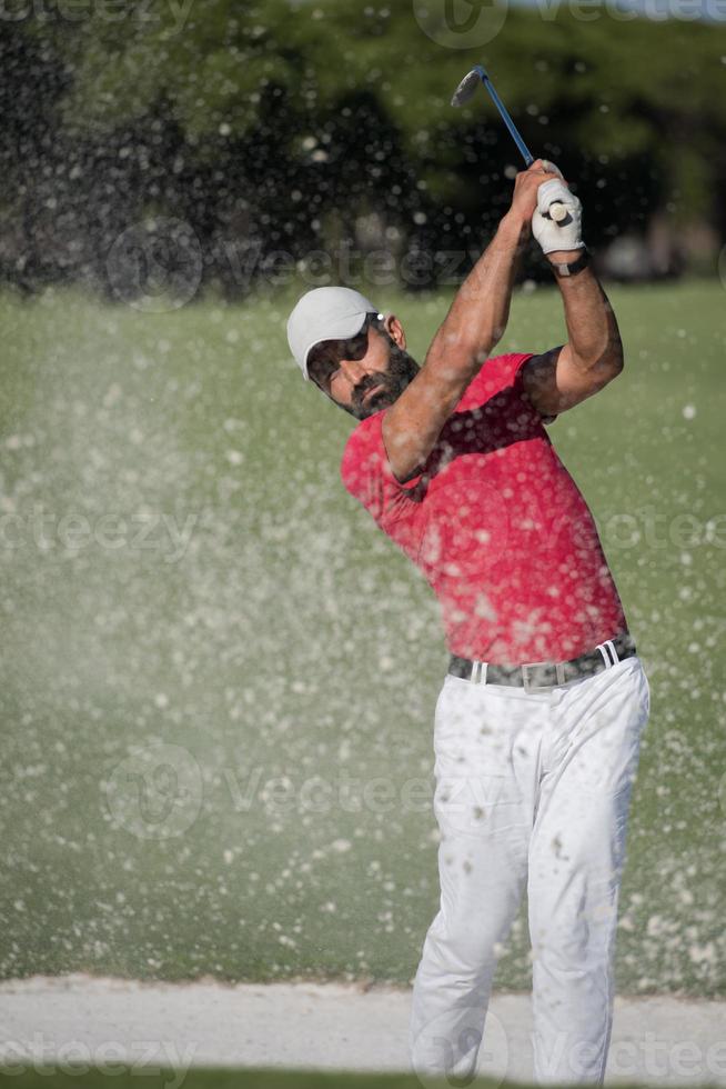 golfer hitting a sand bunker shot photo