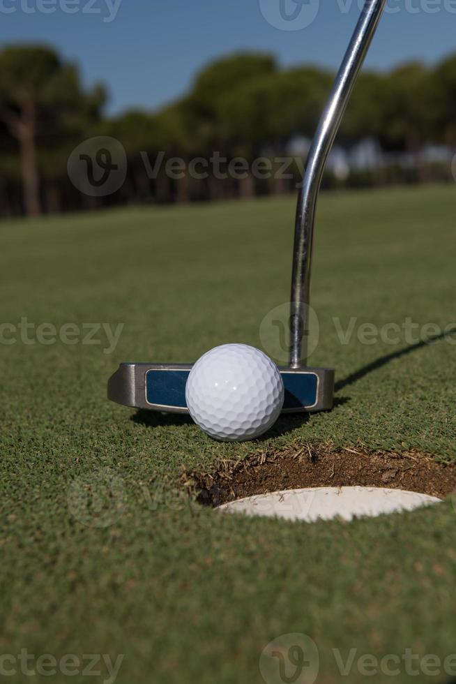 golpear la pelota de golf en el hoyo foto