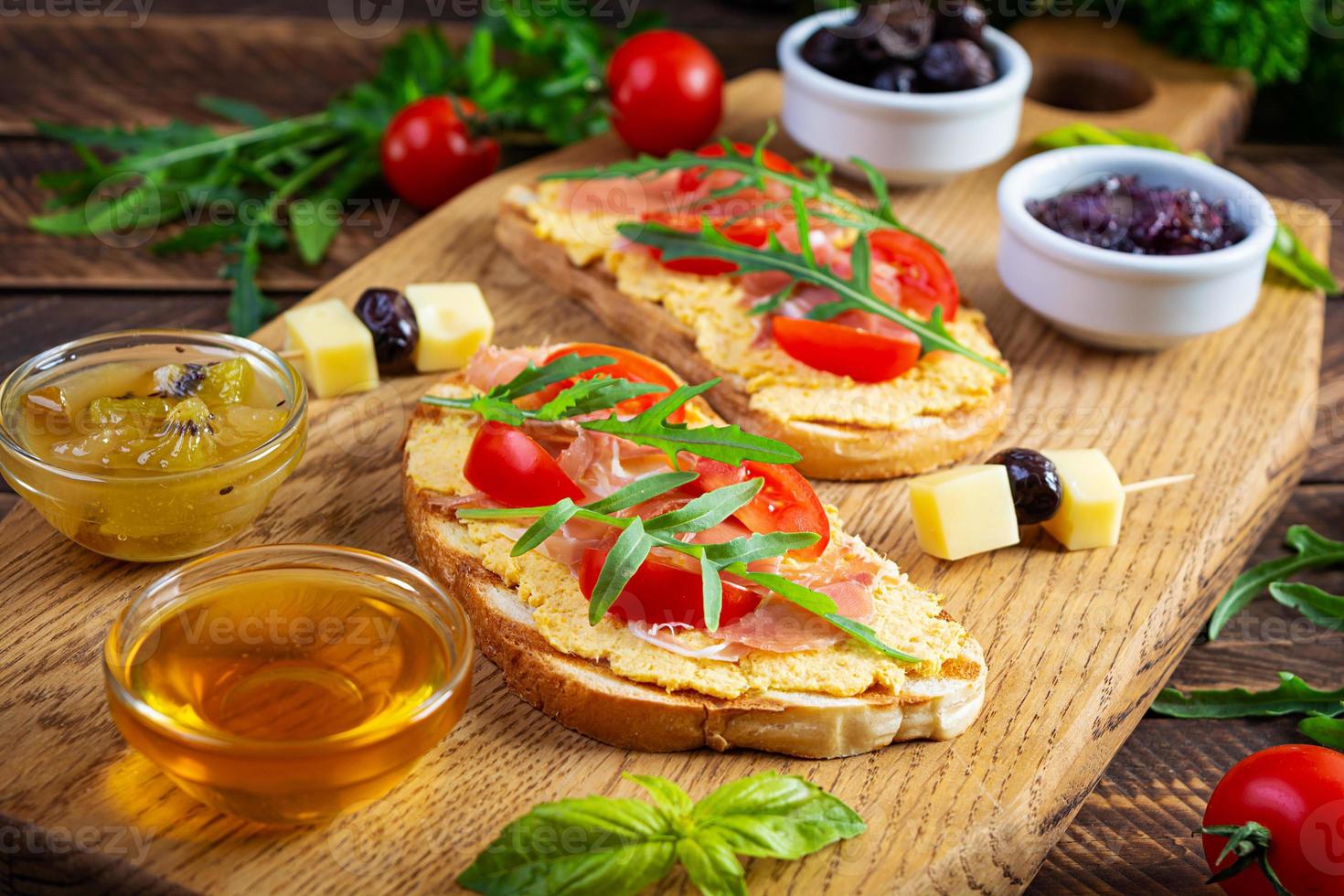 Grilled bruschetta with chicken rillettes, jamon and herbs. Delicious toast with chicken pate and different appetizers photo