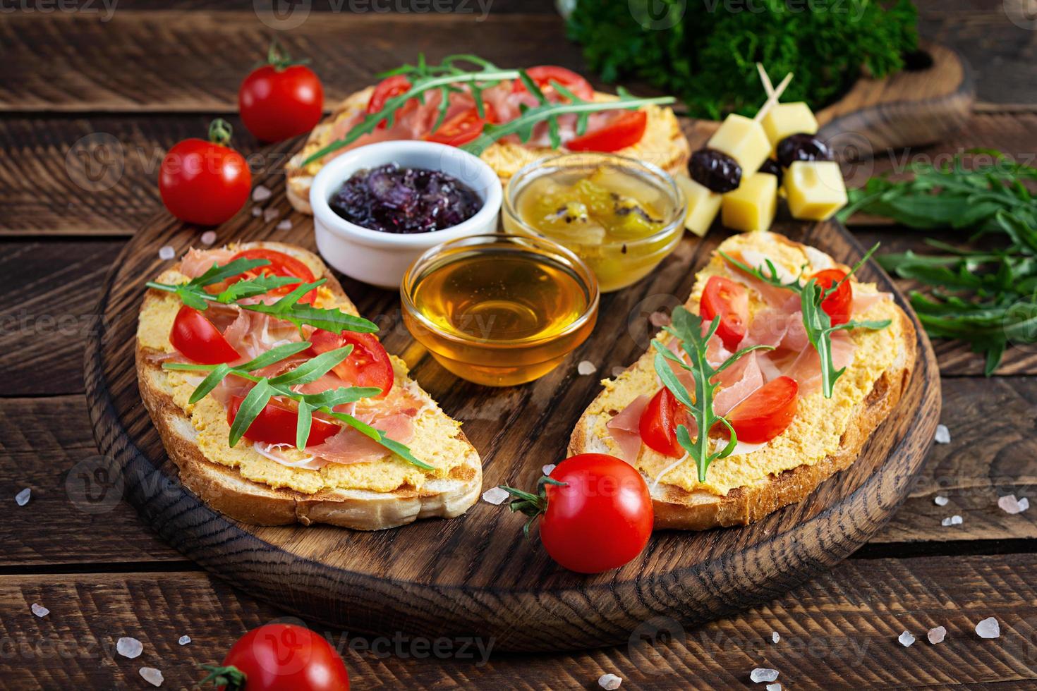 bruschetta a la parrilla con rillettes de pollo, jamón y hierbas. deliciosa tostada con paté de pollo y diferentes aperitivos foto