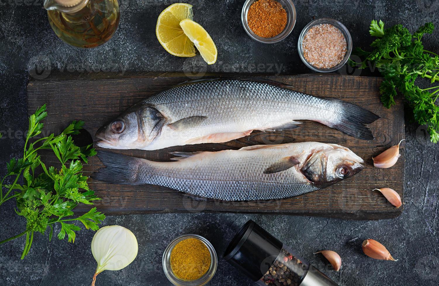 Raw fresh sea bass with different spices on cutting board. Top view photo