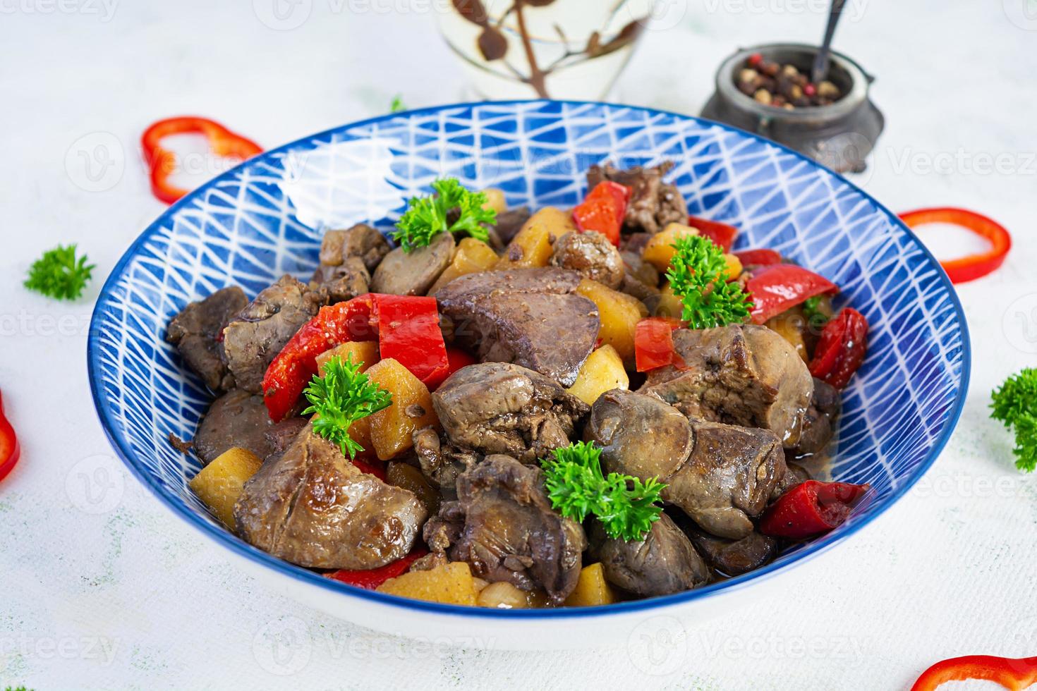 Delicious fried chicken liver with pepper, apples and herbs on light wooden background photo