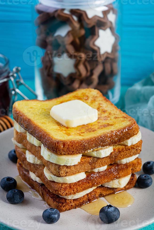 torrija con plátano, arándanos, miel y mermelada de fresa. delicioso desayuno matutino o brunch con tostadas y galletas foto