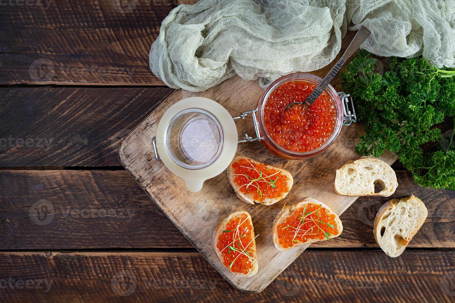 delicioso caviar rojo fresco con tostadas de baguette sobre fondo de madera. vista superior foto