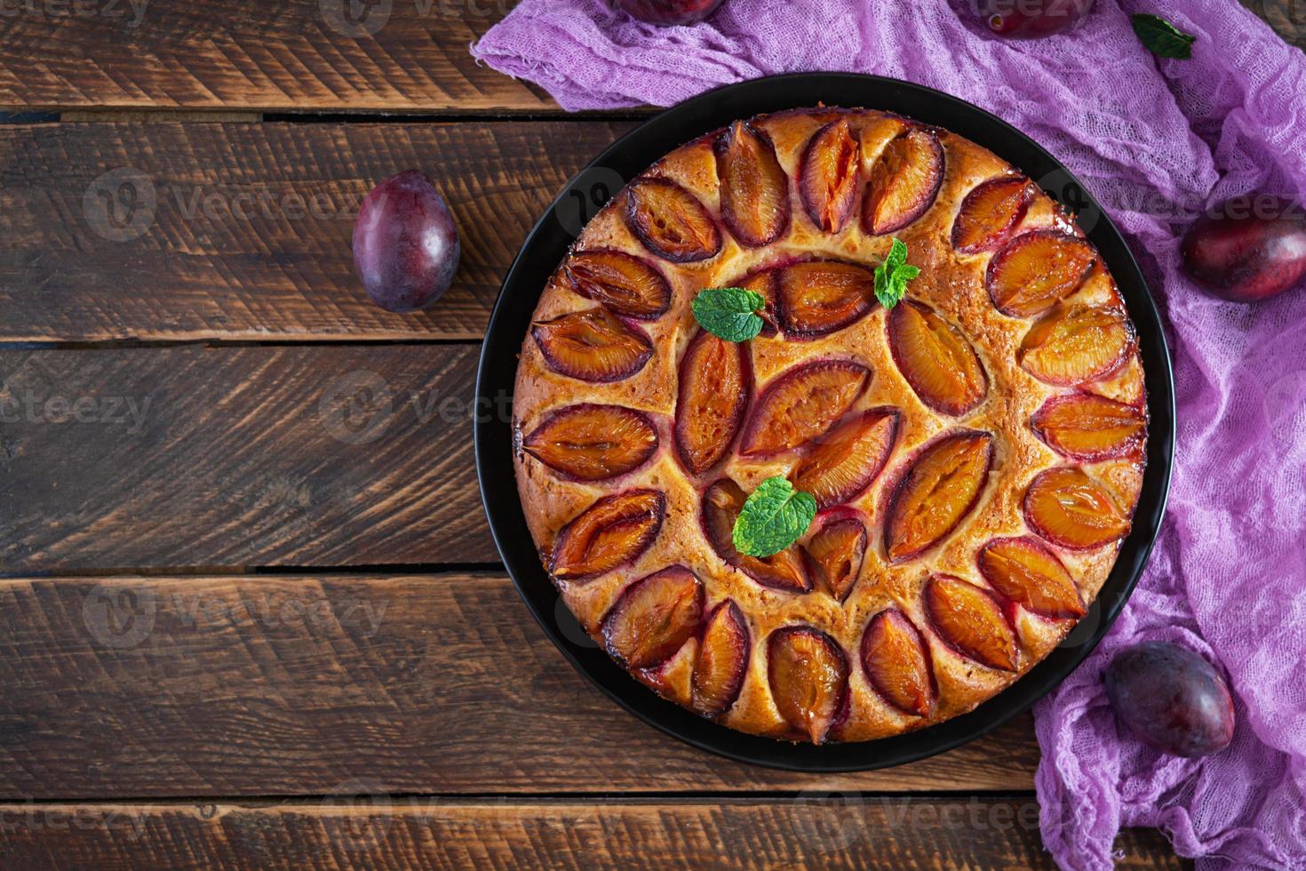 Delicious plum cake on wooden background. Homemade plum pie. Top view photo