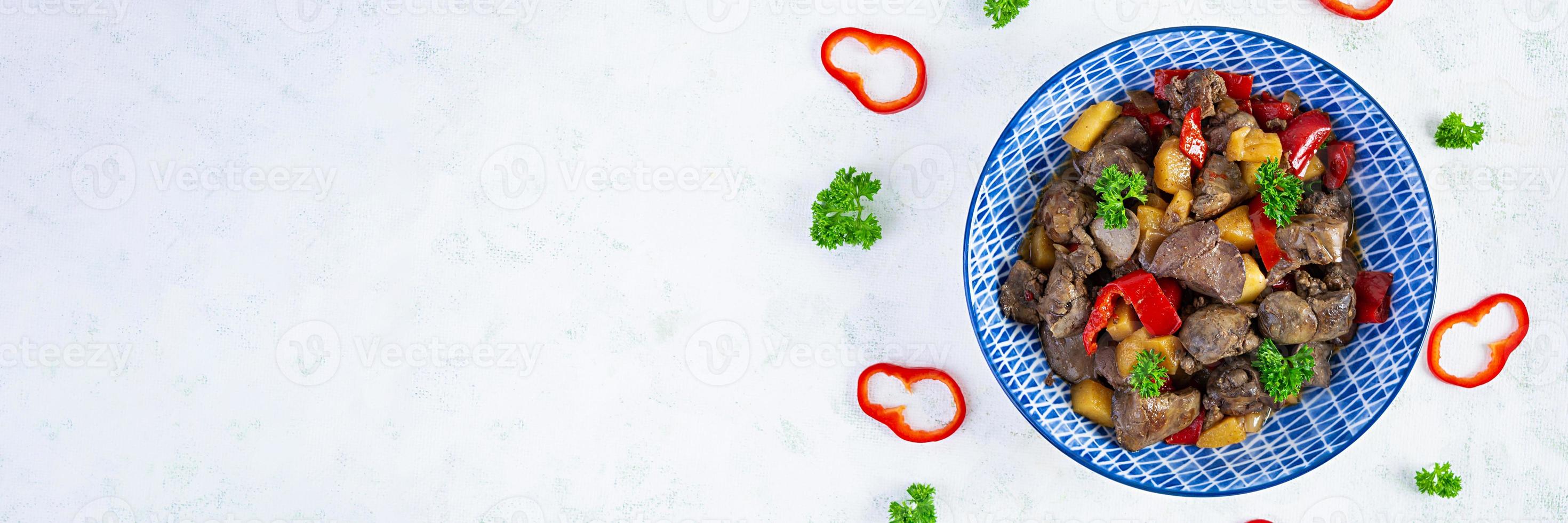 Delicious fried chicken liver with pepper, apples and herbs on light wooden background. Top view photo