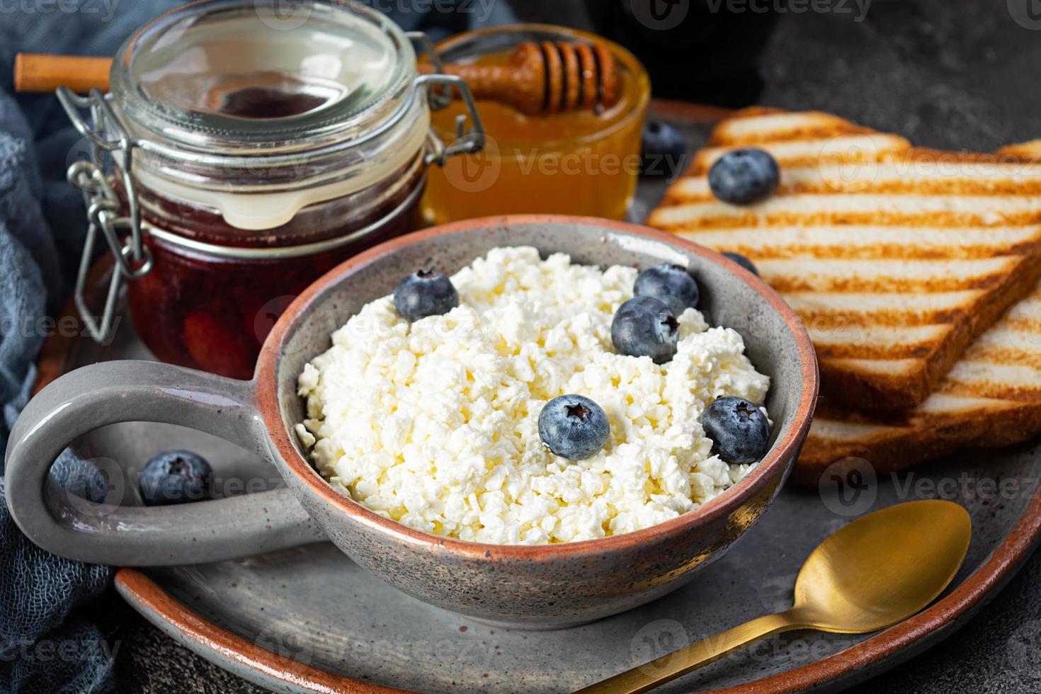 delicioso requesón con arándanos, miel, mermelada de fresa y tostadas. desayuno saludable foto