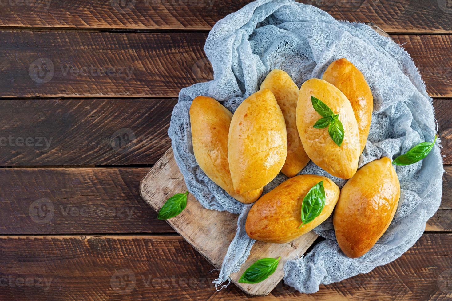 Traditional Russian cabbage pies on wooden background. Baked homemade pirozhki with cabbage. Top view photo