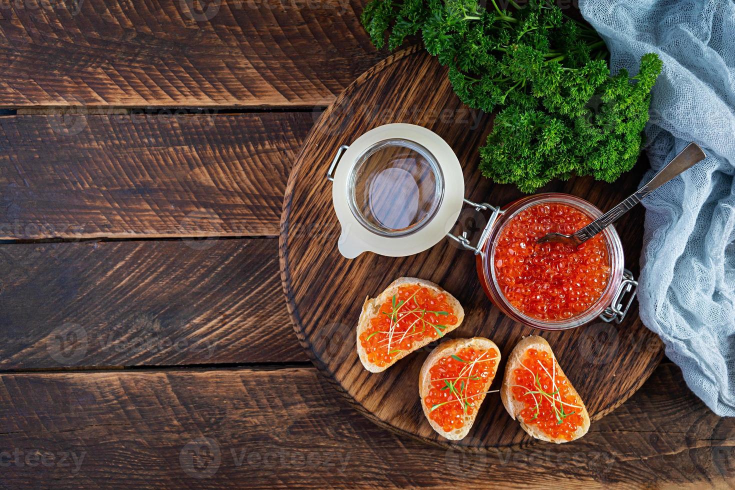 delicioso caviar rojo fresco con tostadas de baguette sobre fondo de madera. vista superior foto