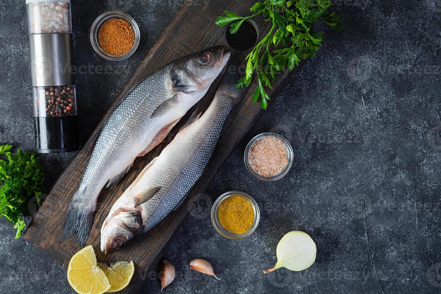 Raw fresh sea bass with different spices on cutting board. Top view photo