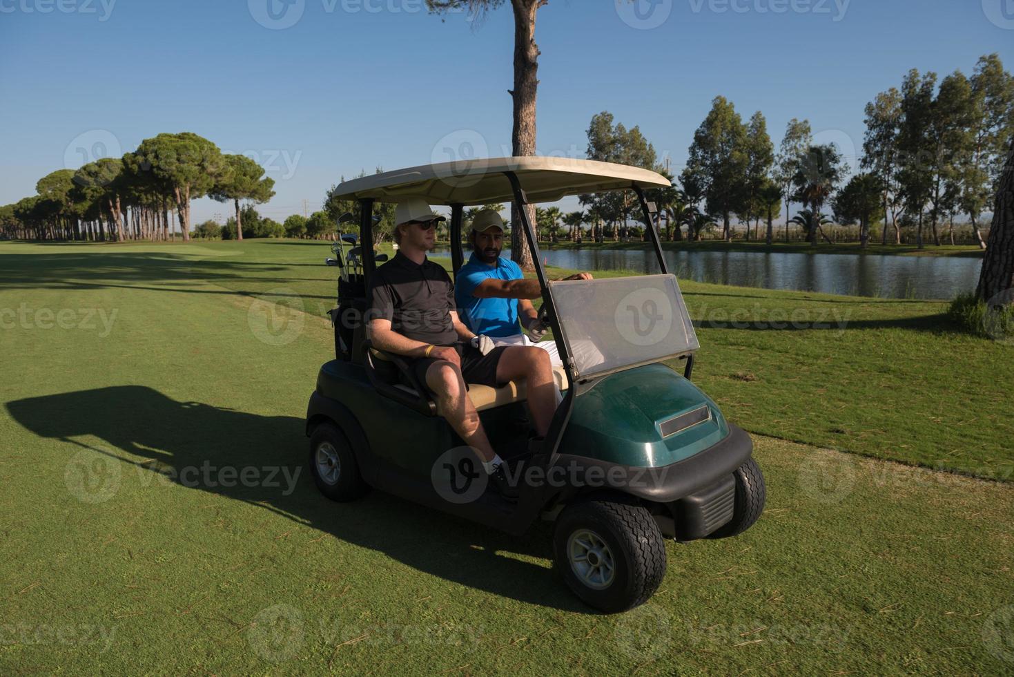 golf players driving cart at course photo