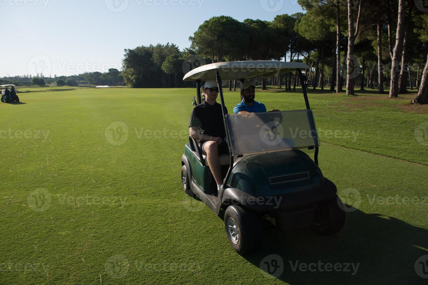 golf players driving cart at course photo