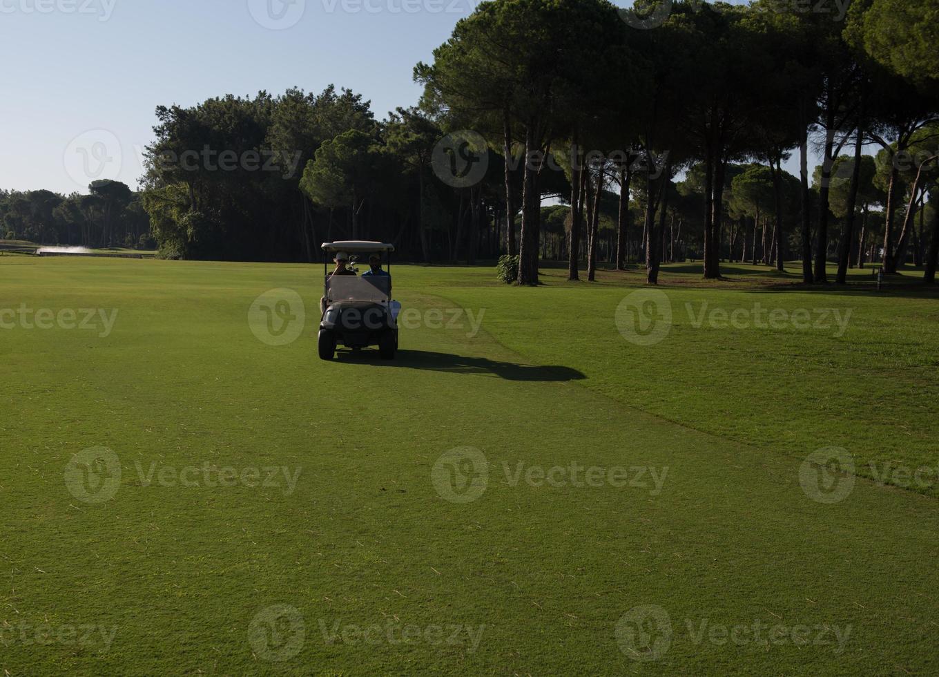 golf players driving cart at course photo