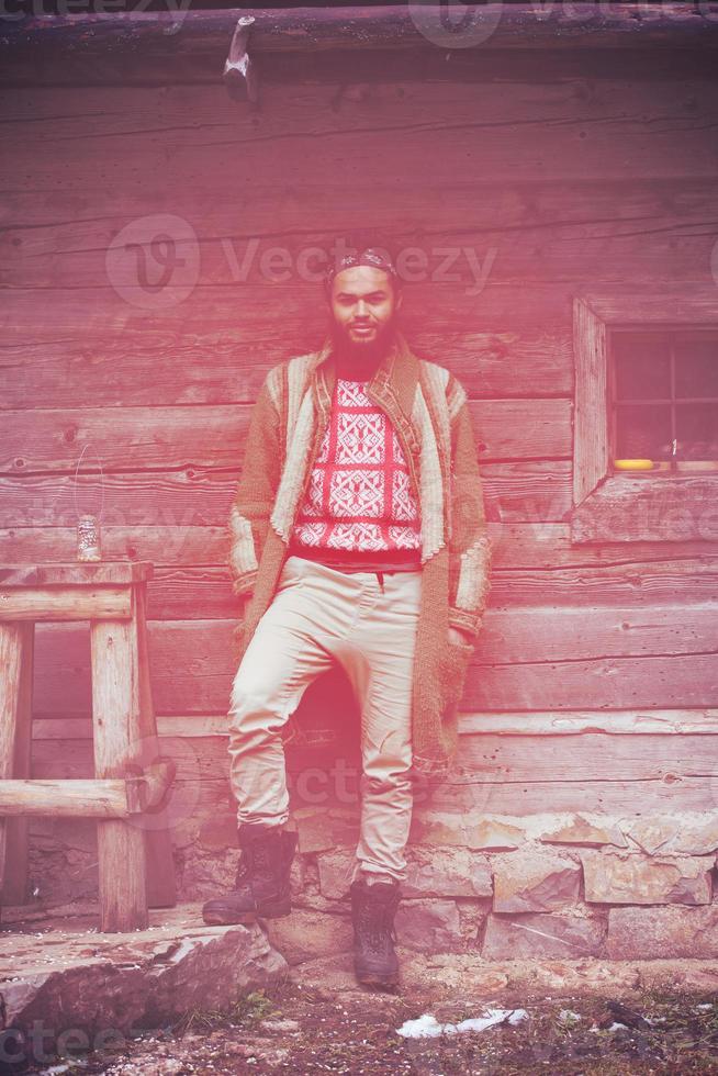 portrait of young hipster in front of wooden house photo