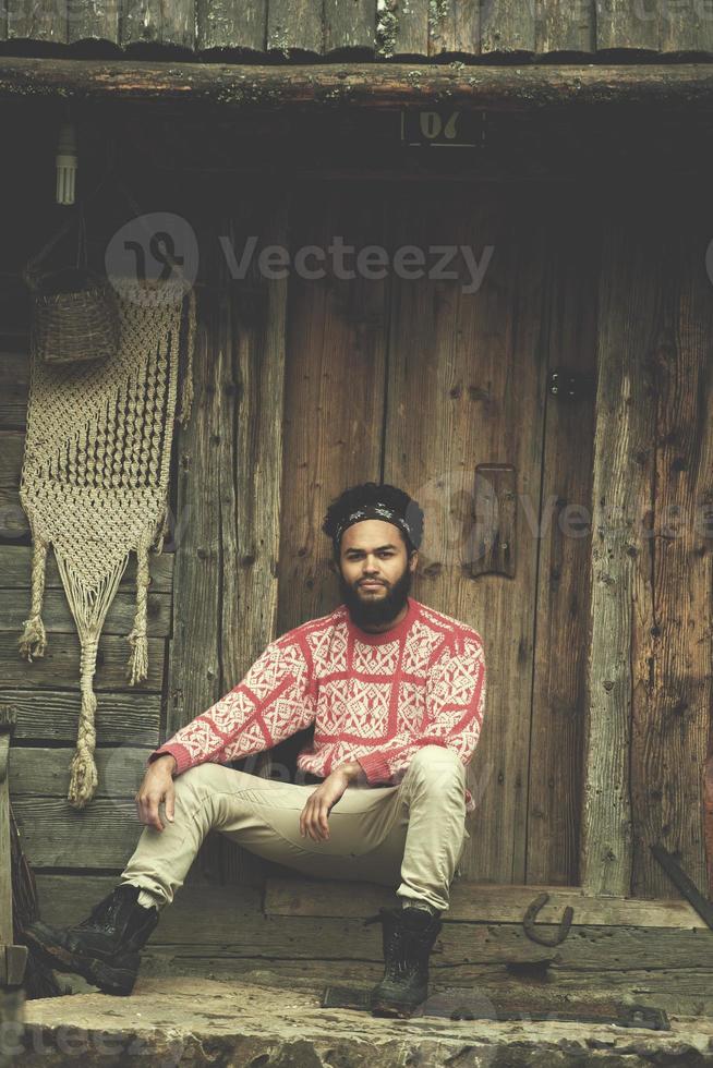 portrait of young hipster in front of wooden house photo