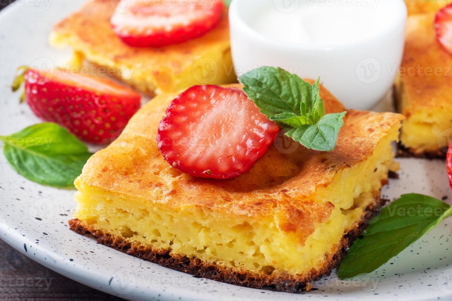 Cottage cheese casserole with strawberries and mint. Delicious homemade dessert made of curd and fresh berries with cream. close up photo