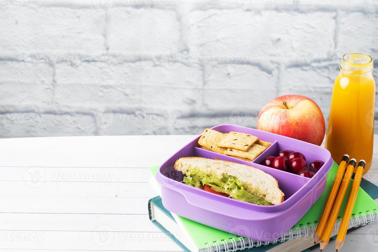 Delicious healthy sandwich in a lunch box, cookies and cherries. Take lunch with you to school or the office. Juice in a bottle and an apple. photo