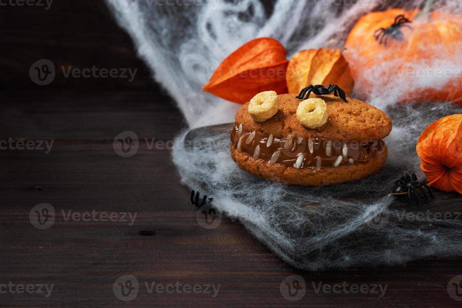 Cookies with cream paste in the shape of monsters for Halloween celebration. Funny homemade faces made of oatmeal cookies and boiled condensed milk. copy space photo