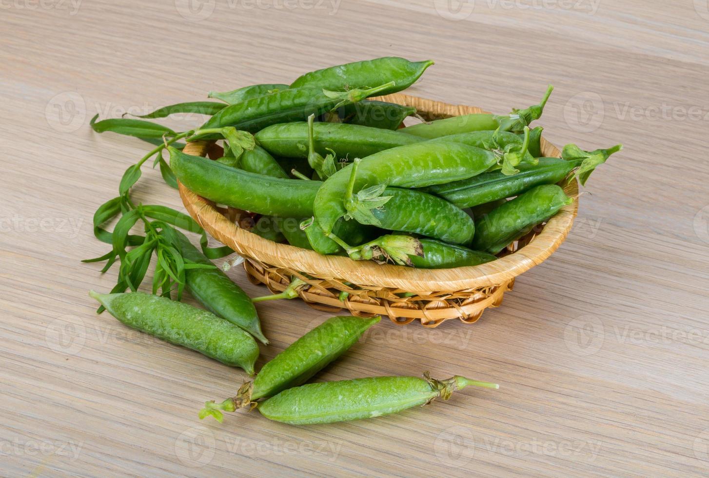 Green fresh peas in a basket on wooden background photo