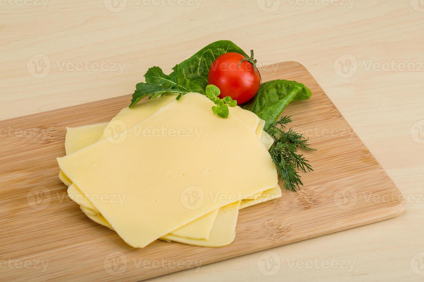 queso en lonchas sobre tabla de madera foto