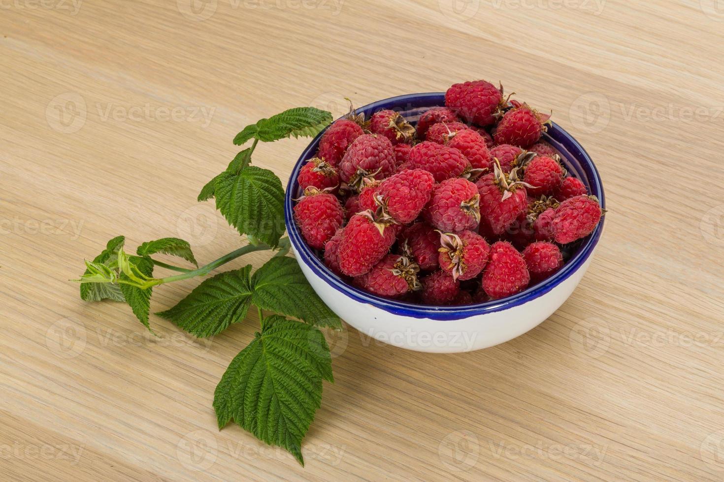 Raspberry in a bowl on wooden background photo