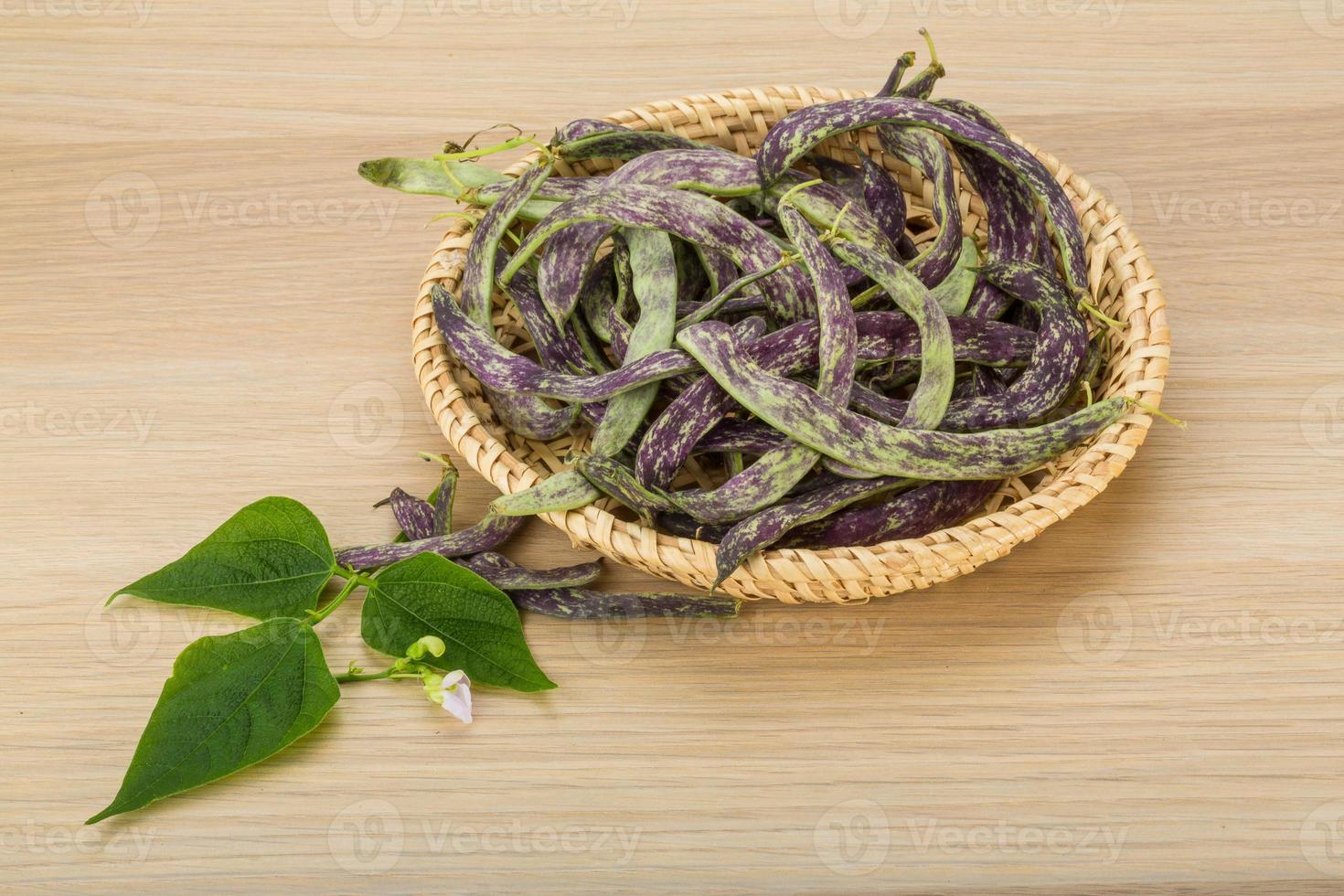 frijoles con hojas en una canasta sobre fondo de madera foto