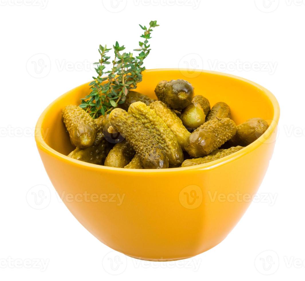 Marinated cucumbers in a bowl on white background photo