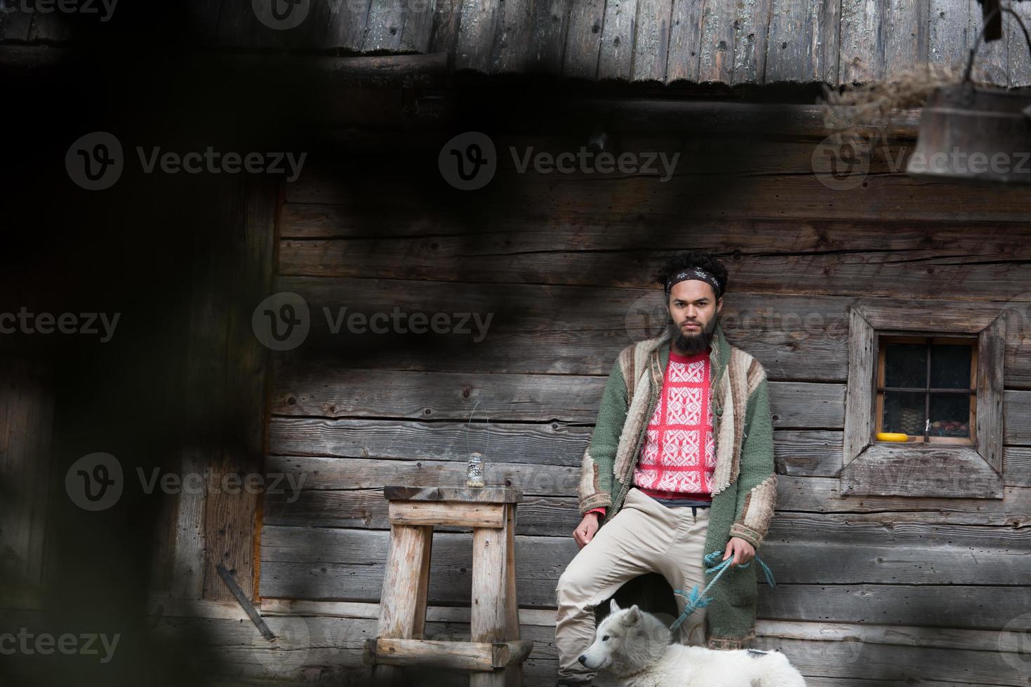 hipster with dog in front of wooden house photo