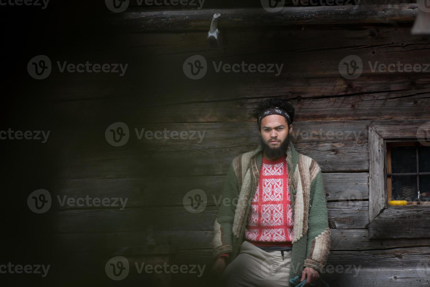 portrait of young hipster in front of wooden house photo