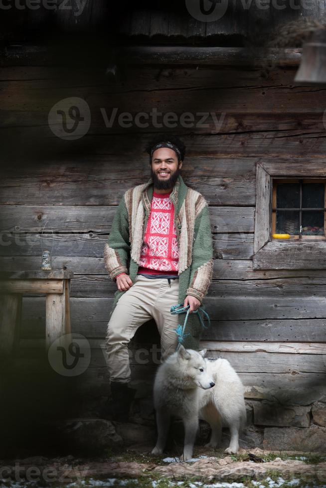 hipster with dog in front of wooden house photo