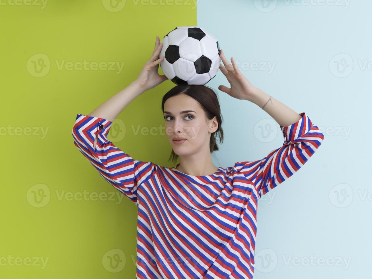 Portrait of young European woman holding soccer ball on her head photo