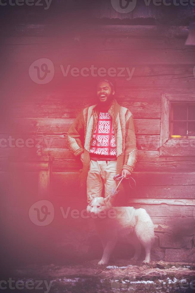 hipster with dog in front of wooden house photo