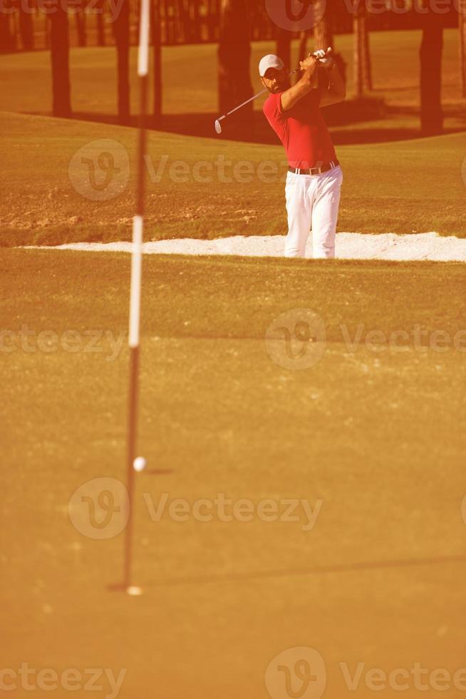 golfista golpeando un tiro de búnker de arena foto