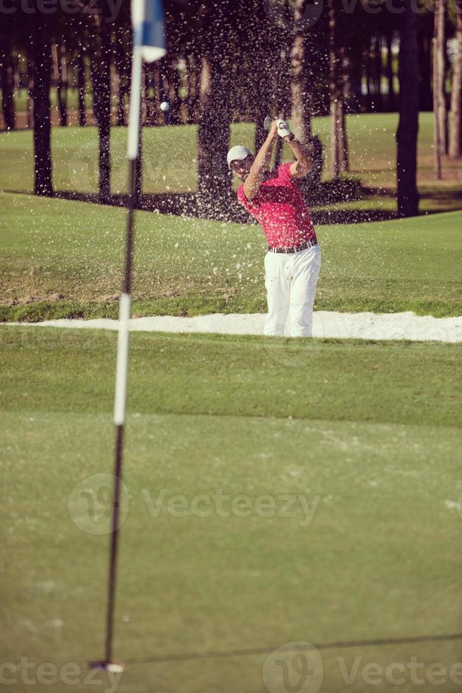 golfer hitting a sand bunker shot photo