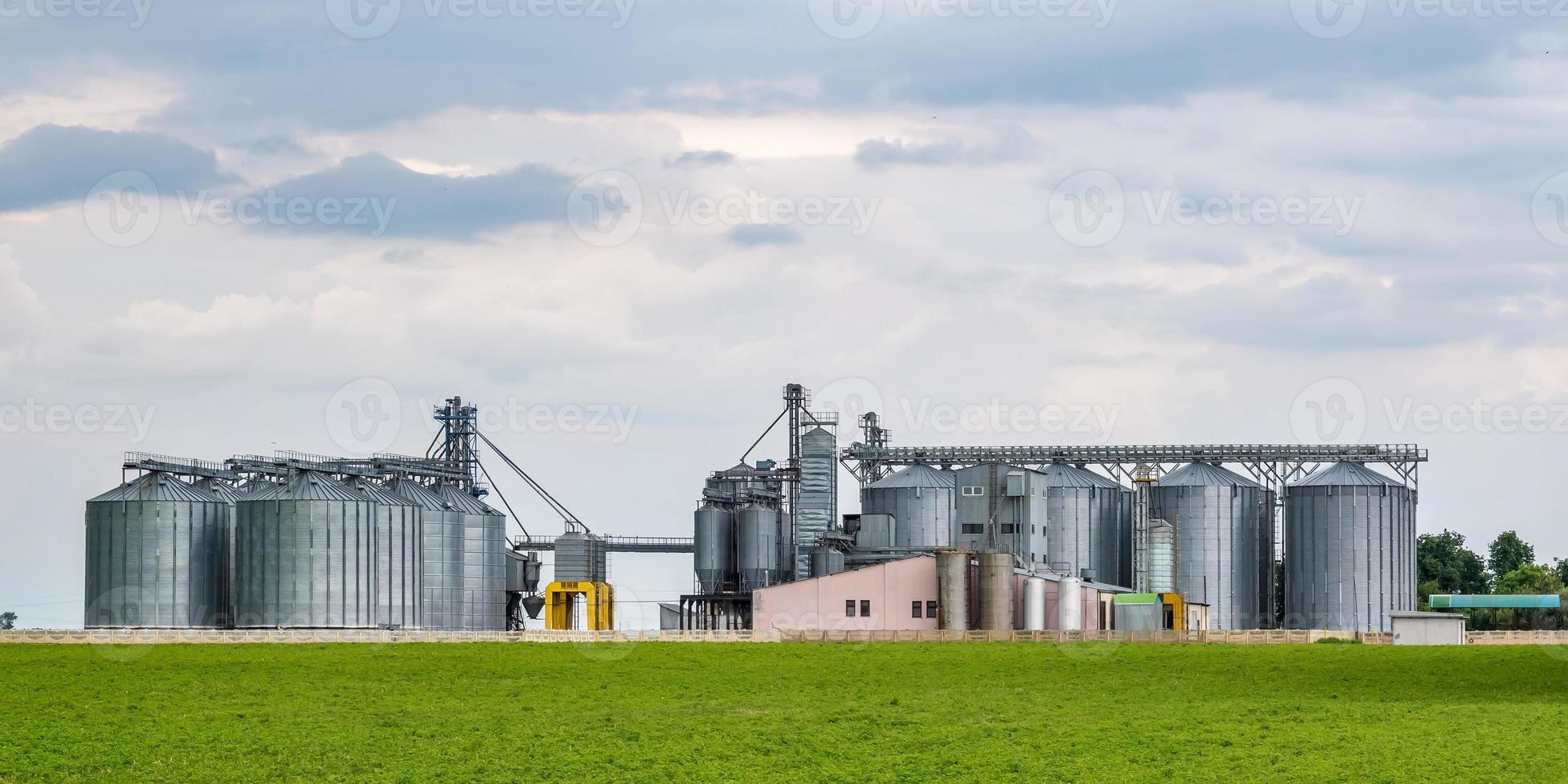 Modern Granary elevator and seed cleaning line. Silver silos on agro-processing and manufacturing plant for processing drying cleaning and storage of agricultural products, flour, cereals and grain. photo