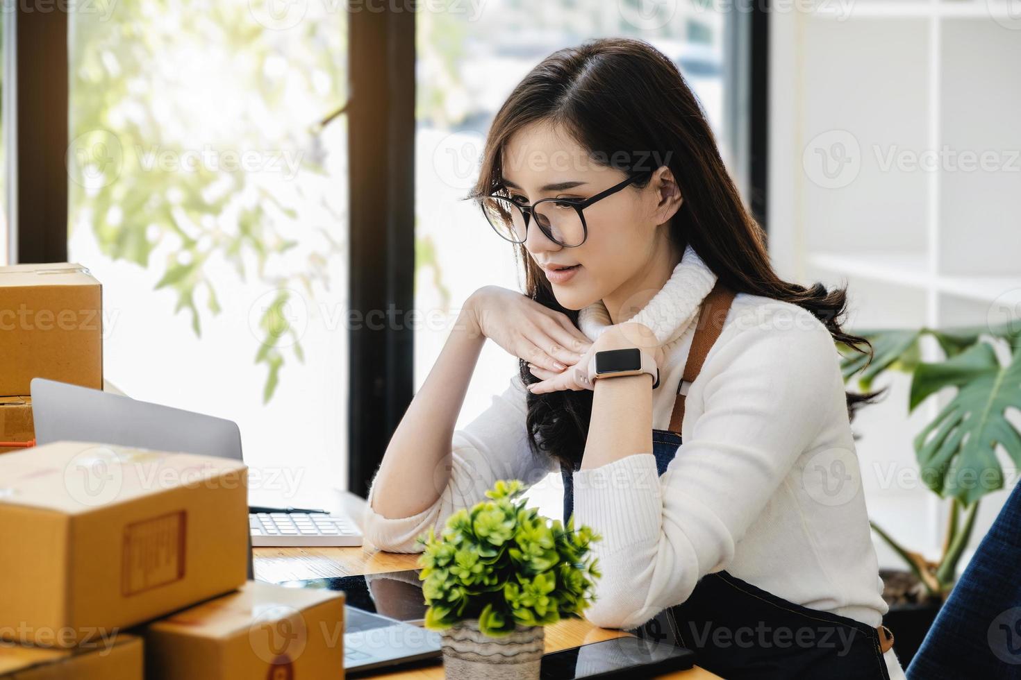 trabajar desde casa. las mujeres felices que venden productos en línea inician una pequeña empresa usando una computadora portátil para calcular los precios y prepararse para el franqueo. foto