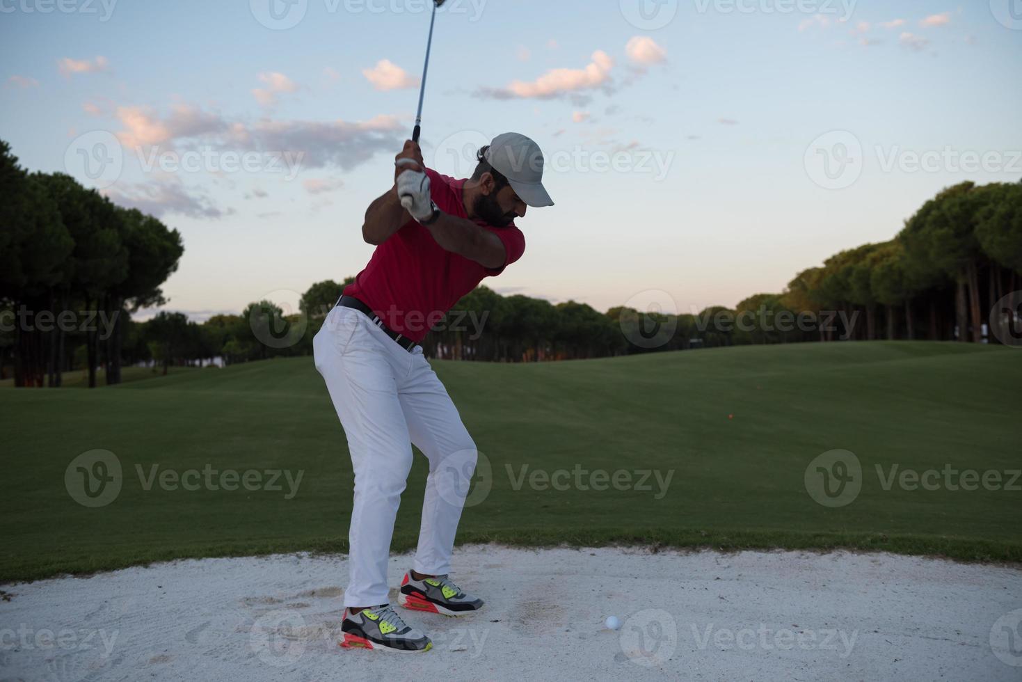 golfer hitting a sand bunker shot on sunset photo