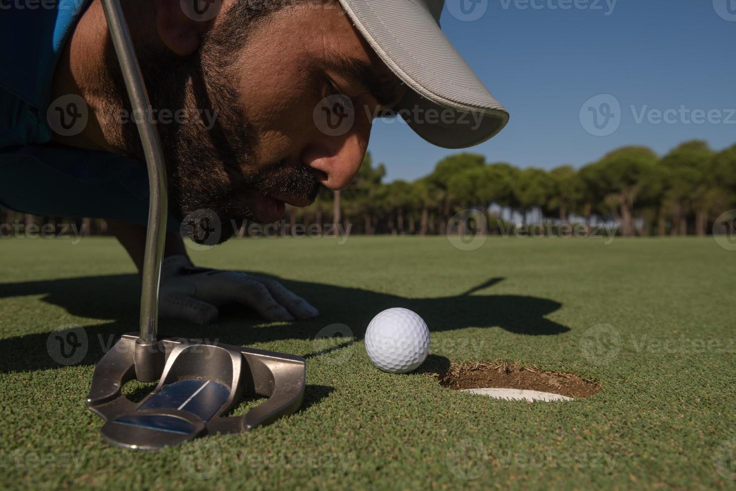 jugador de golf que sopla la bola en el agujero foto