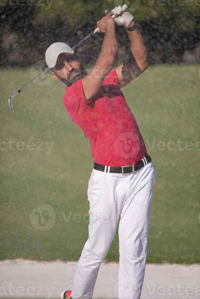 golfer hitting a sand bunker shot photo