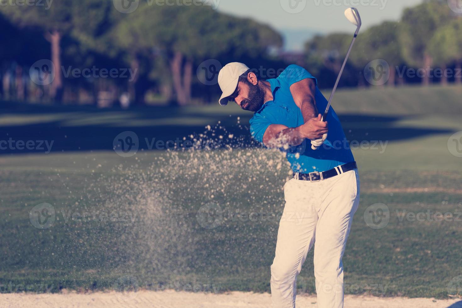 golfista profesional golpeando un tiro de búnker de arena foto