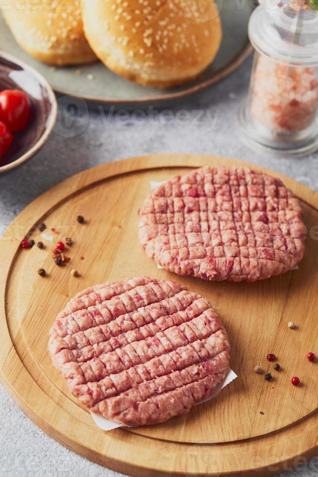 carne picada de ternera cruda chuletas de bistec de hamburguesa en tabla de cortar de madera foto