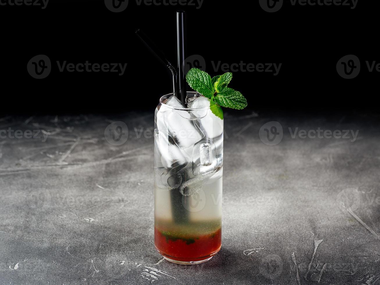 Cold alcoholic or non-alcoholic cocktail with ice on dark background photo