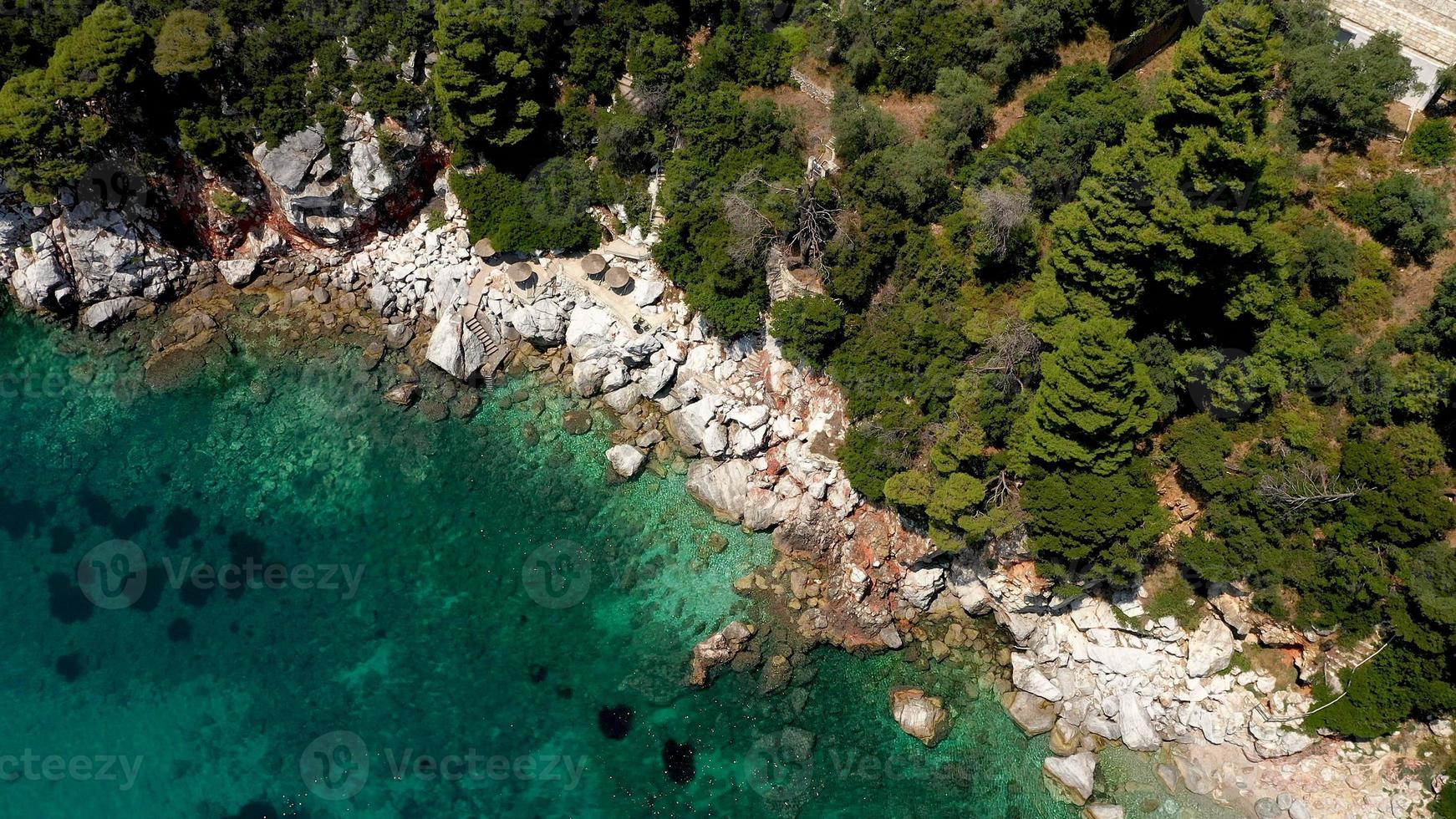 vistas aéreas de drones sobre una costa rocosa, aguas cristalinas del mar Egeo, playas turísticas y mucha vegetación en la isla de skopelos, grecia. una vista típica de muchas islas griegas similares. foto